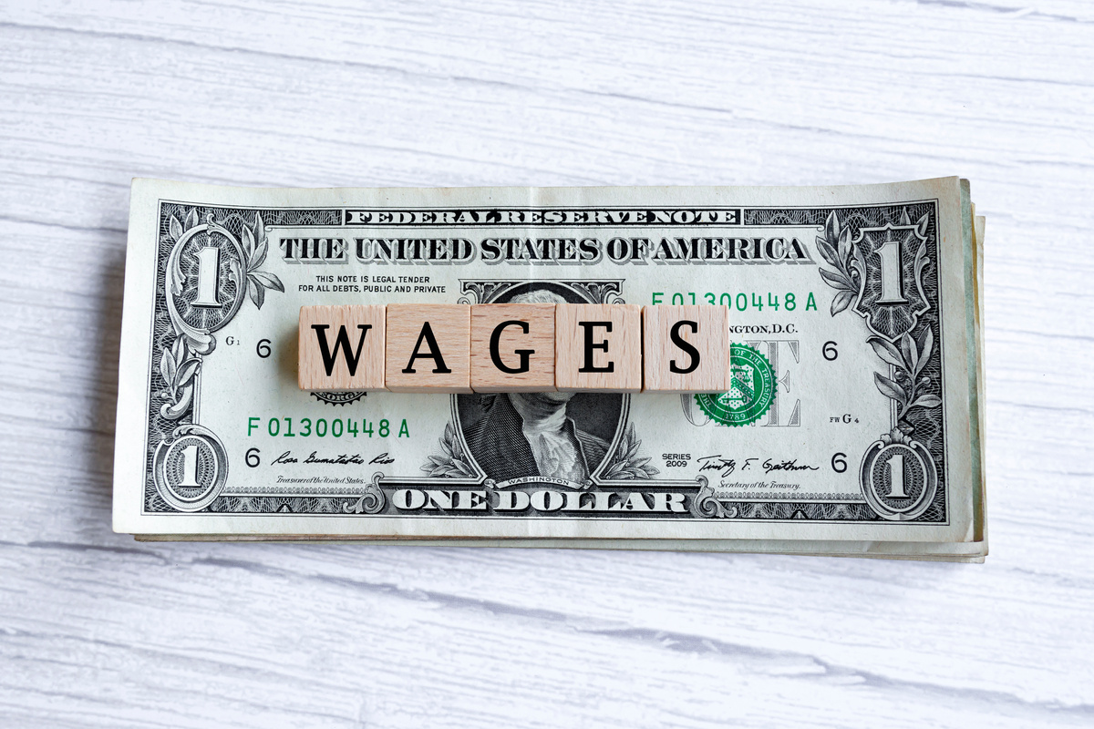 Wages word written on wood block with American Dollar-bills.